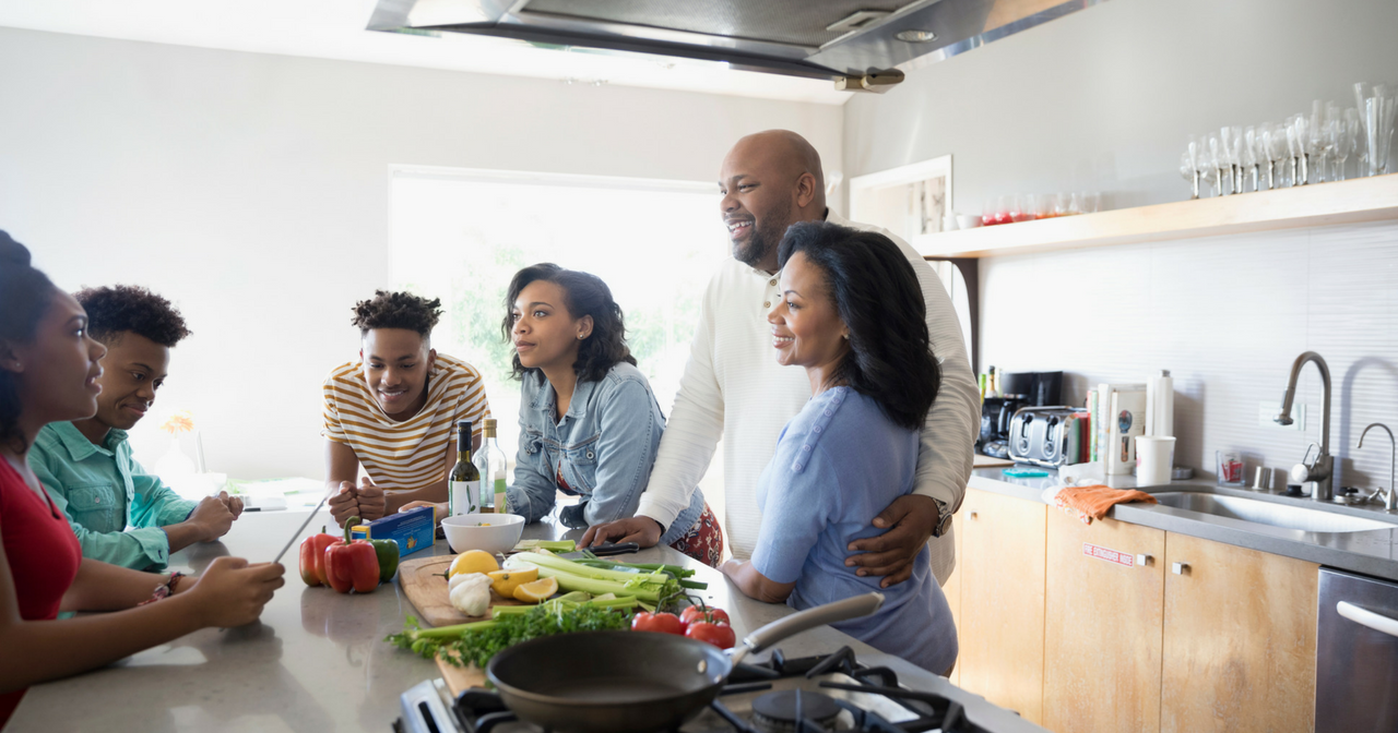 A family stands around a kitchen island and talks