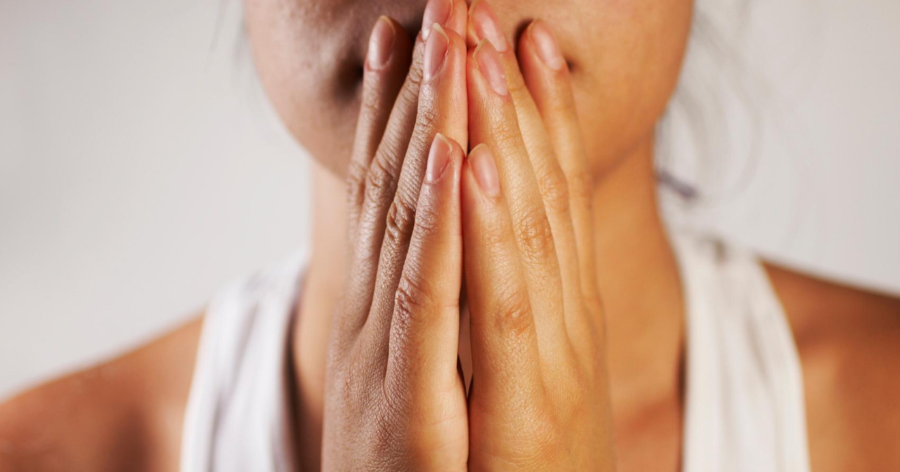 A close up of a woman's hands covering her mouth in a worried fashion. 