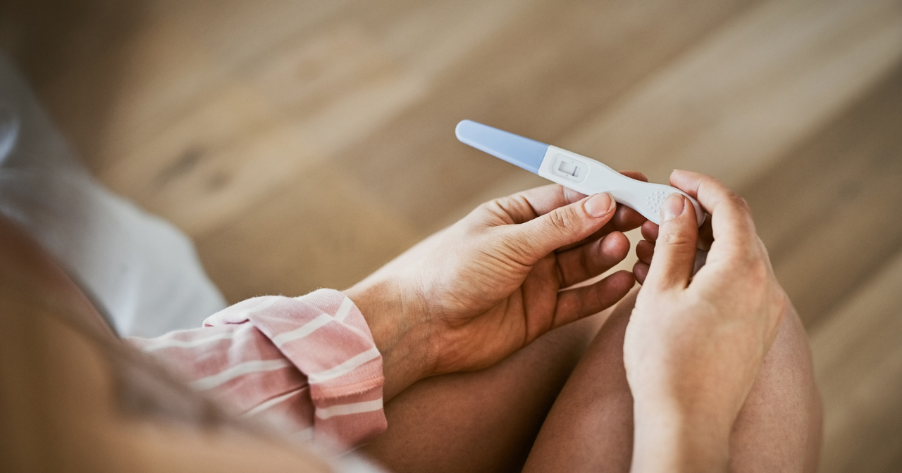 A pair of hands hold a pregnancy test. 