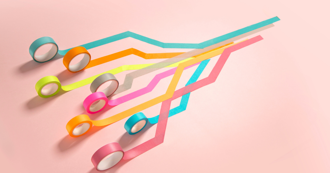 Eight different colors of tape are all rolled out and over one another. 