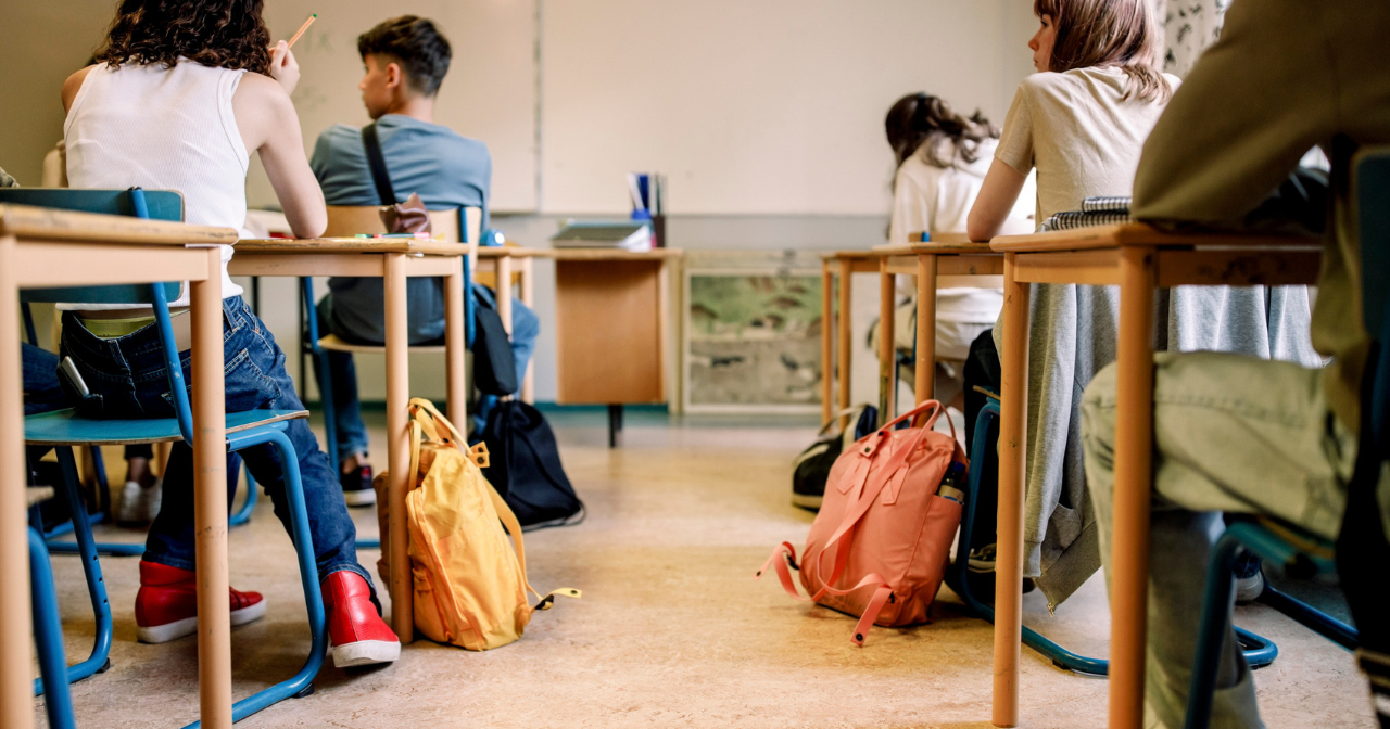 A photo of a full classroom from the back looking towards the board. 