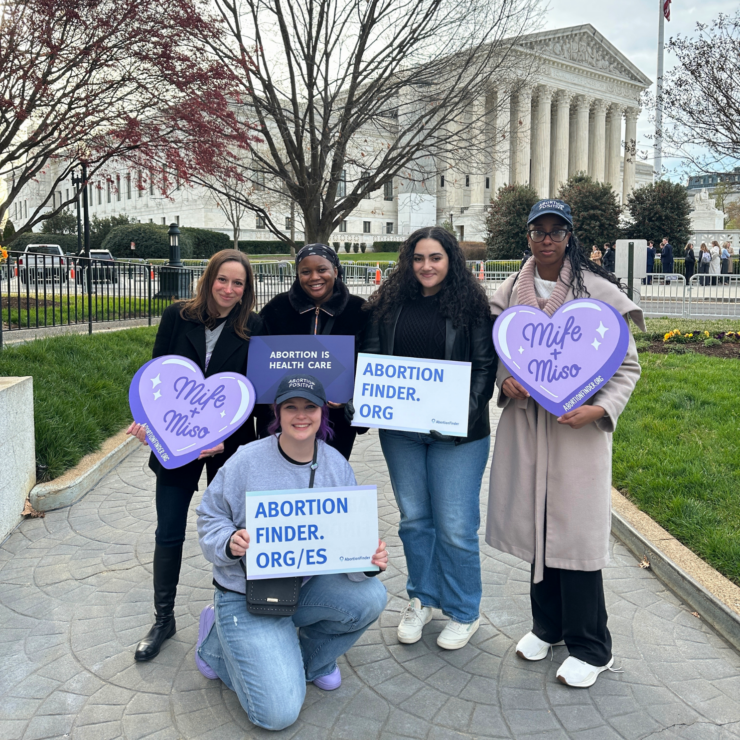 Power to Decide staff stand in front of the Supreme Court while holding abortion positive signs. 