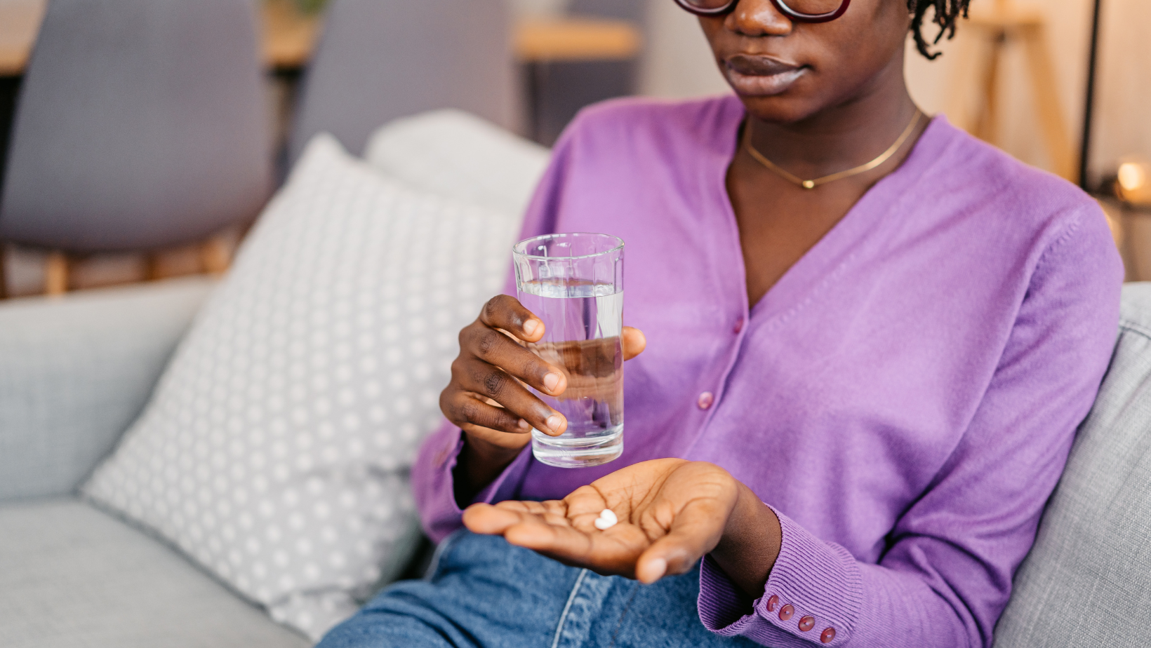 Woman taking a pill with water.