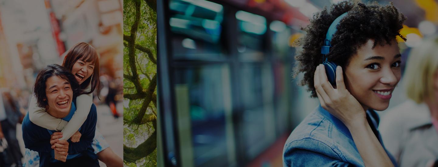 Woman rides piggyback on her boyfriend and another woman wearing headphones smiles at the camera