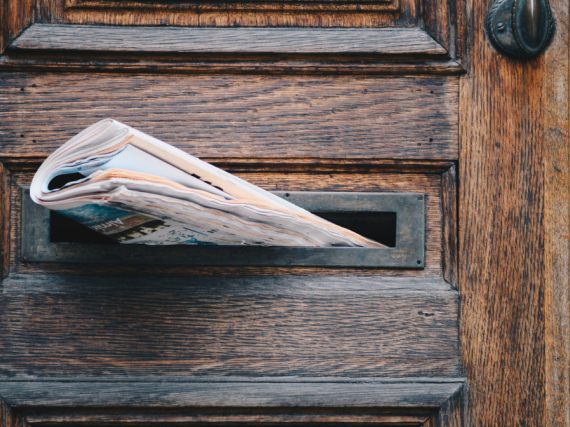 a newspaper sticking out of a mail slot of a door
