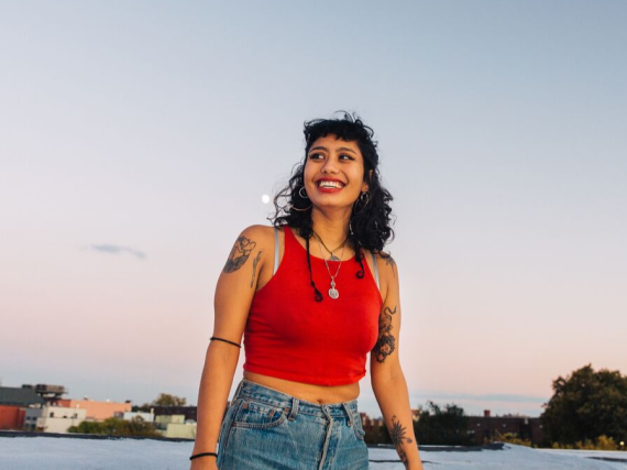 A woman smiles a large smile outside against the moonrise