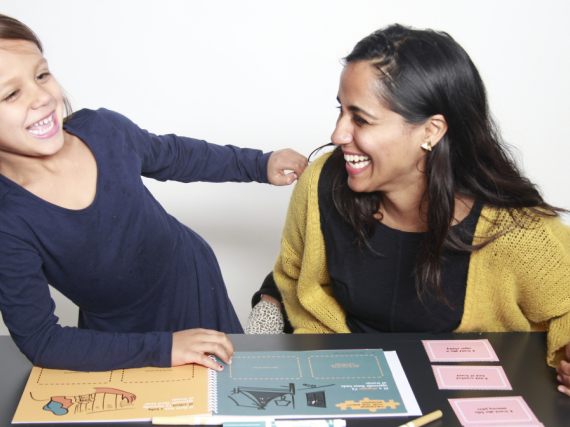 A mother and daughter laugh together while going through a Bloom playbook. 