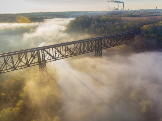 A photo of a bridge in Appalachian Kentucky surrounded by fog with sun beams peaking through. 